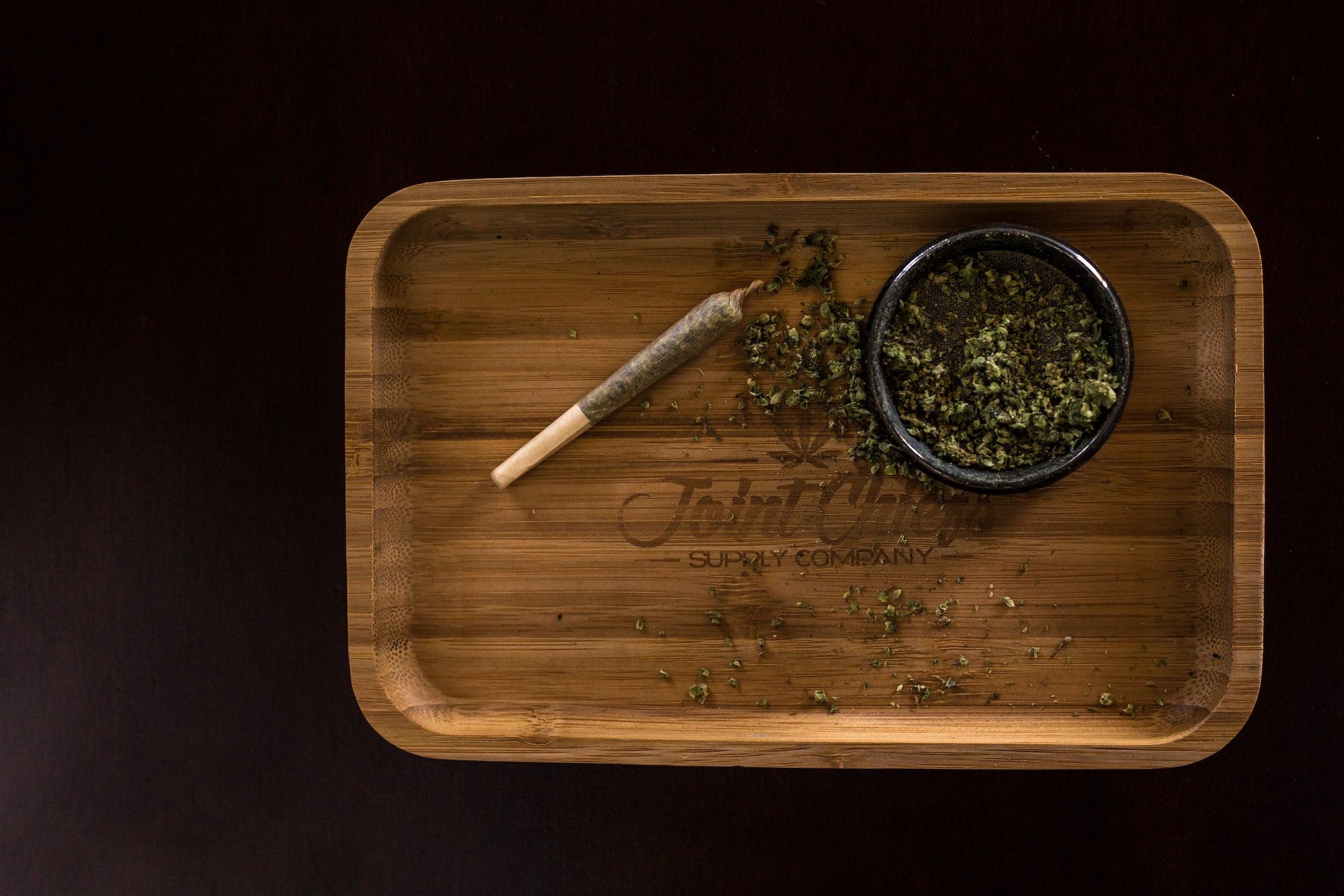 Bamboo rolling tray with a finished joint and ground flower in a small bowl